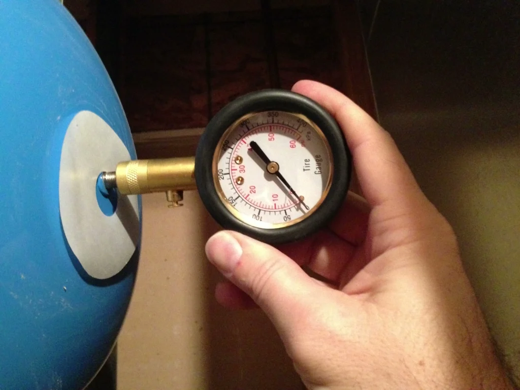 Checking the Schrader valve on a well pressure tank with a tire pressure gauge