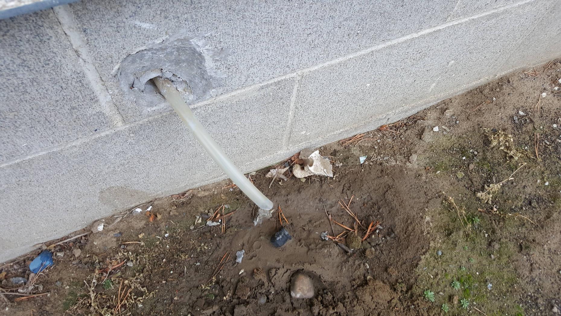 Clear vinyl condensate discharge tubing routed along basement ceiling joists with a visible kink near a bracket