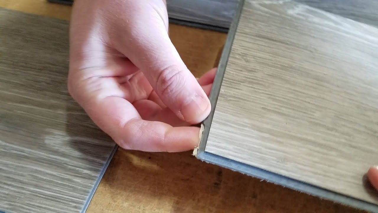 Close-up photo of a vinyl plank locking edge with a chipped tongue and missing material along the click profile