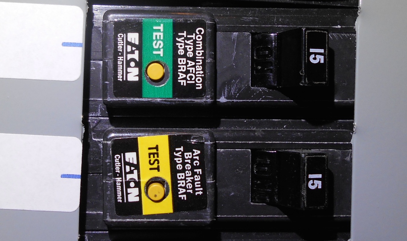 Close-up photo of an AFCI or GFCI style circuit breaker in a residential panel with a visible test button and toggle switch