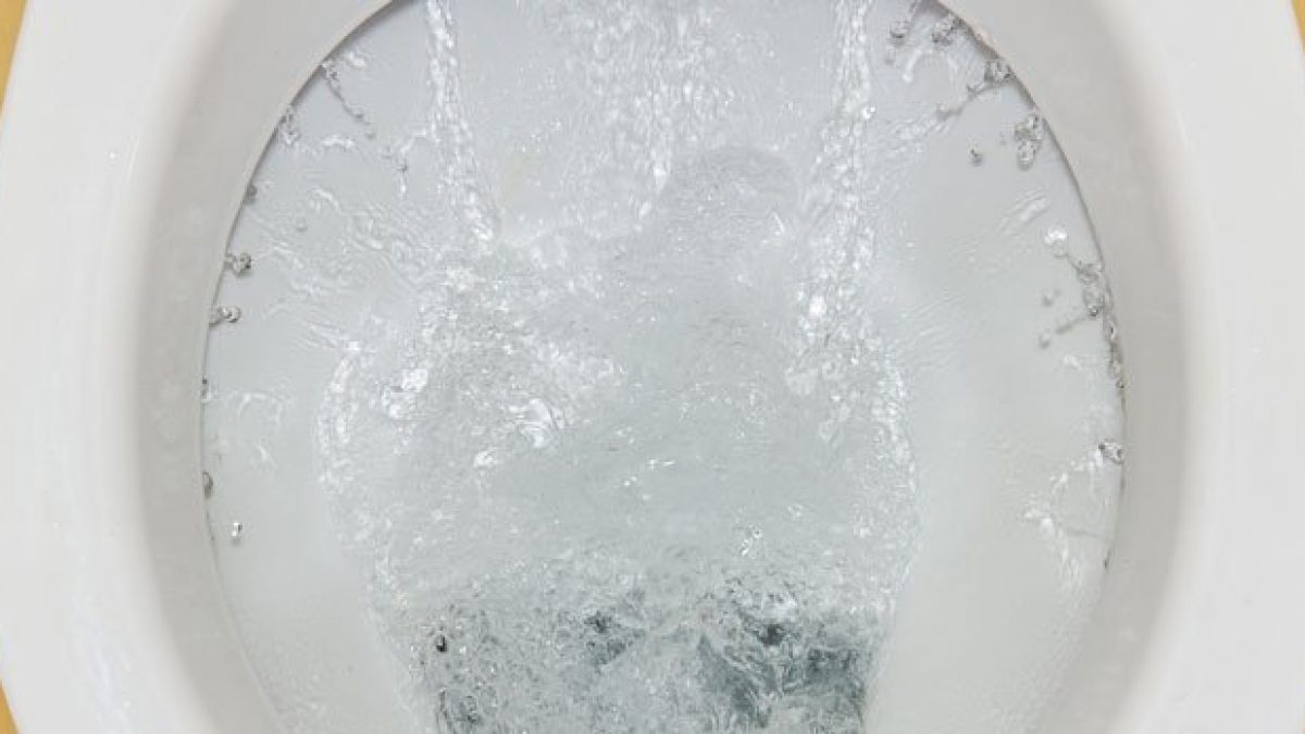 Close-up photo of the underside of a toilet bowl rim showing small rim jet openings with visible mineral buildup