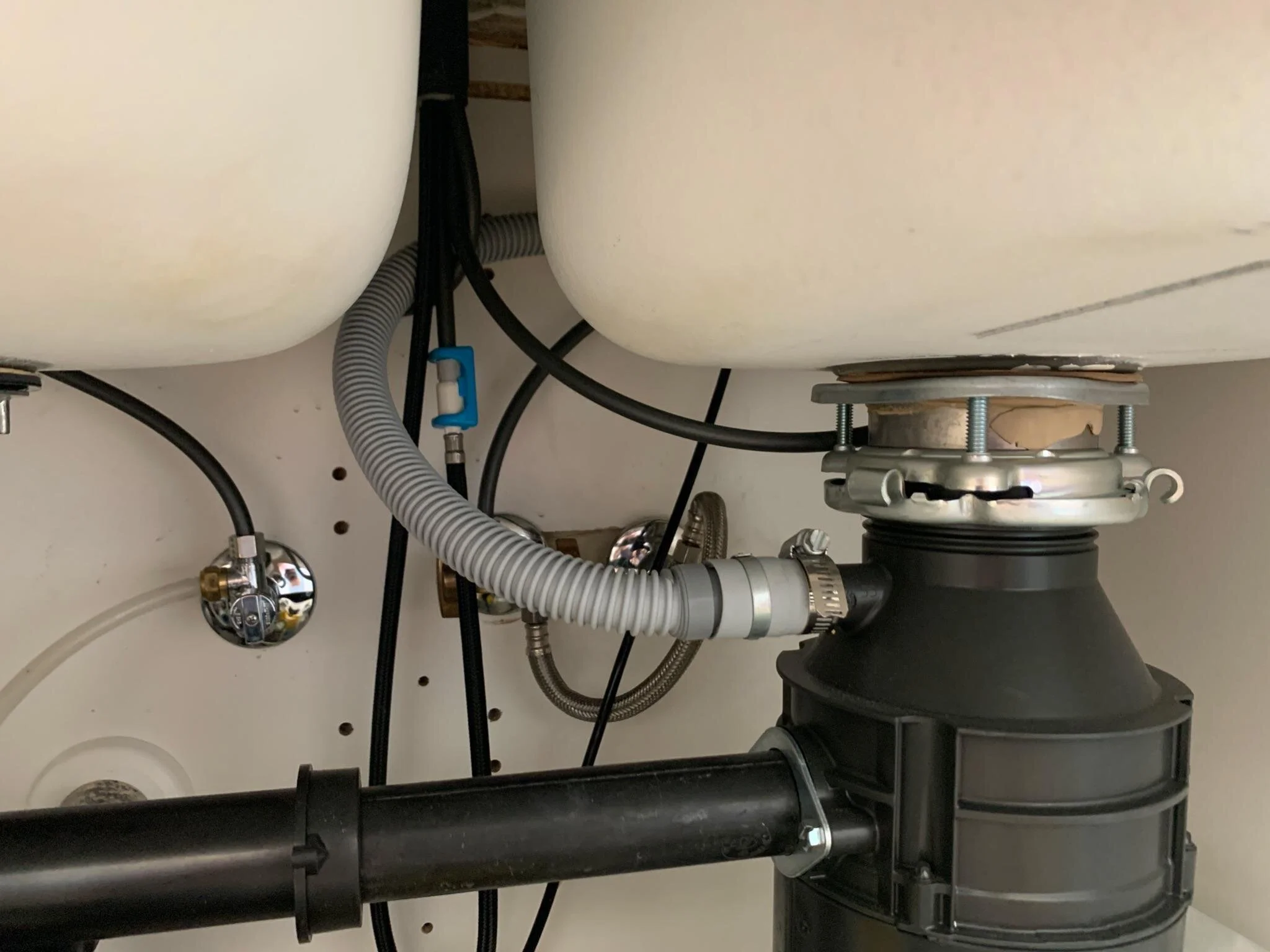 Dishwasher drain hose secured in a high loop beneath the countertop before connecting to the sink drain