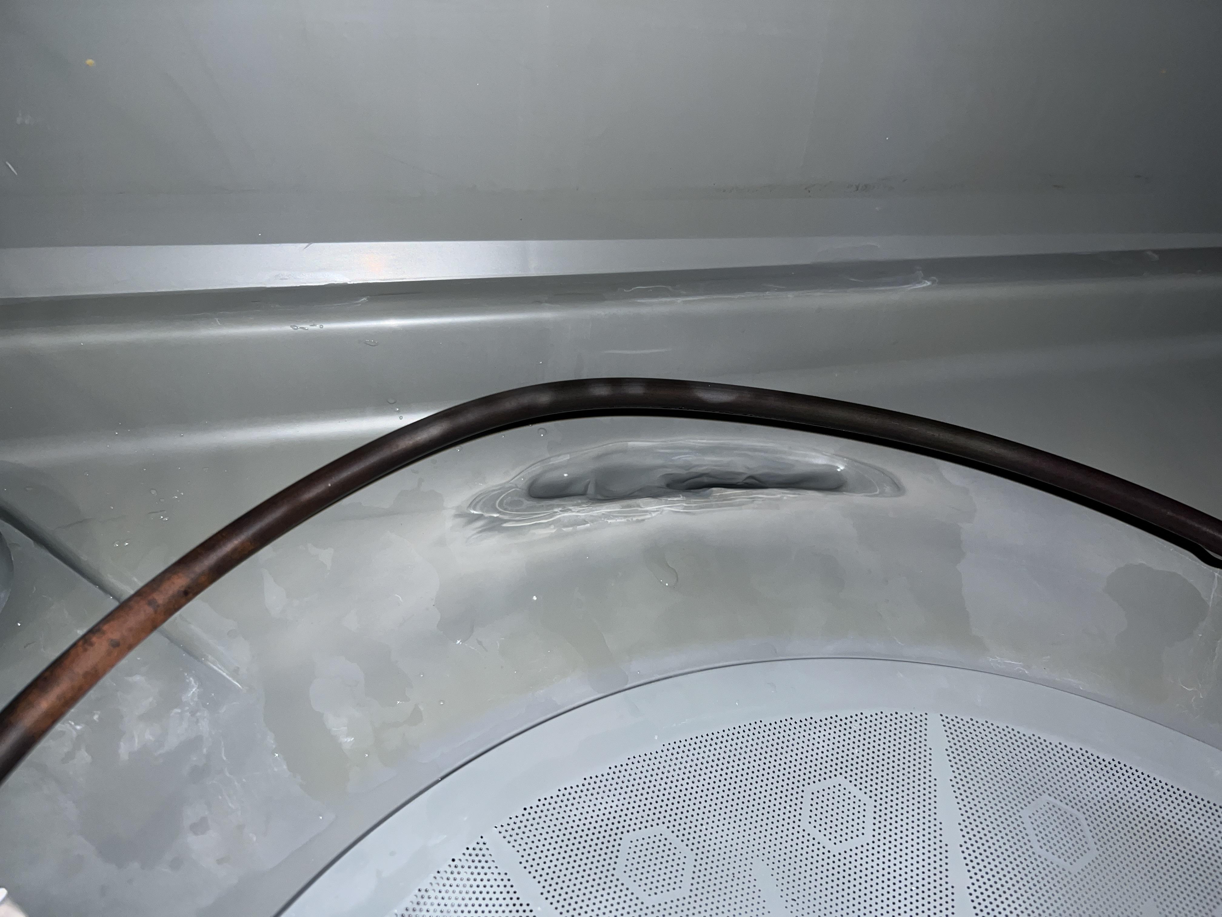 Melted dark plastic stuck to a dishwasher heating element area near the bottom of the tub