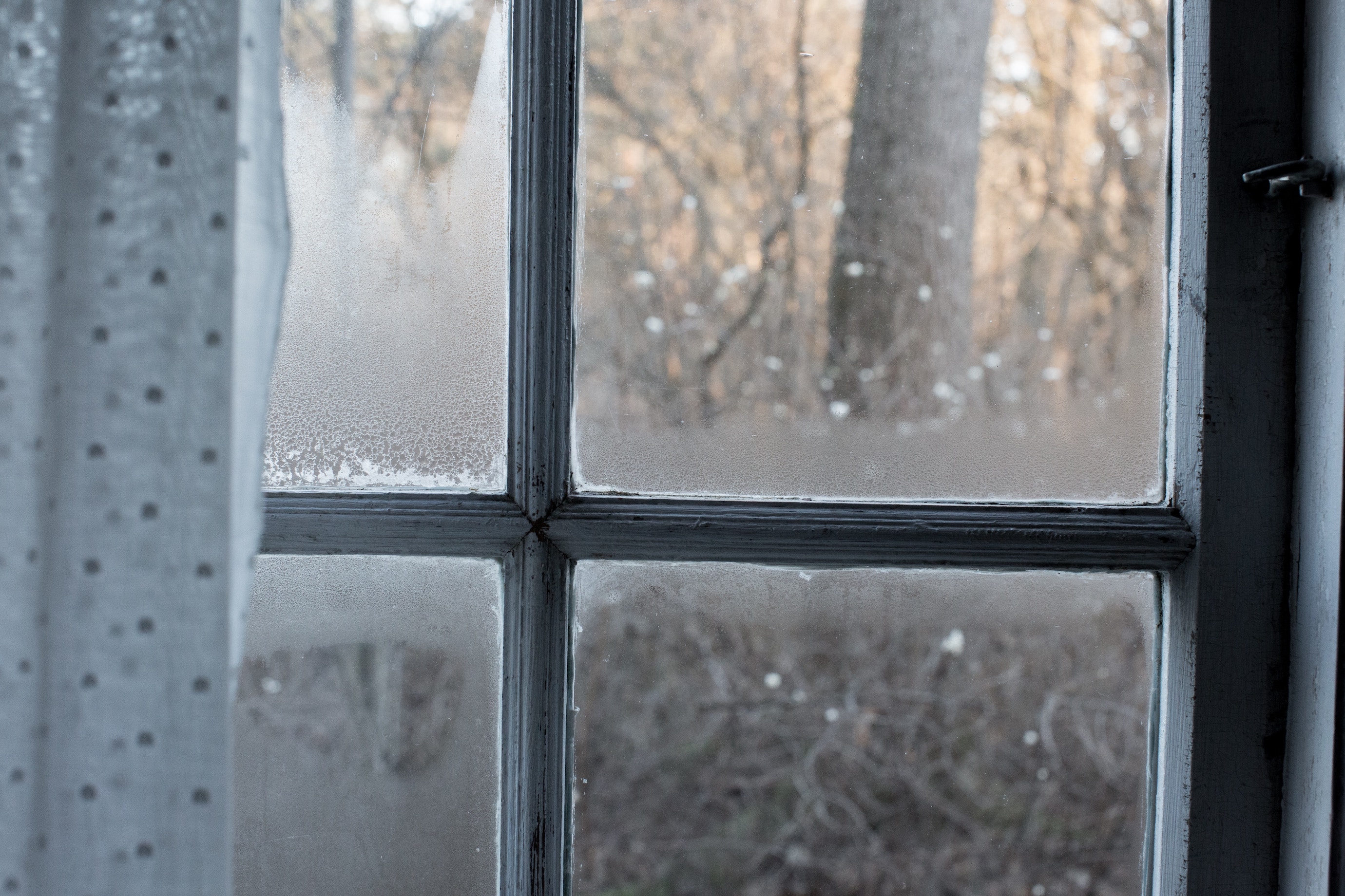 Moisture condensation collecting along the bottom edge of an interior window during cold weather
