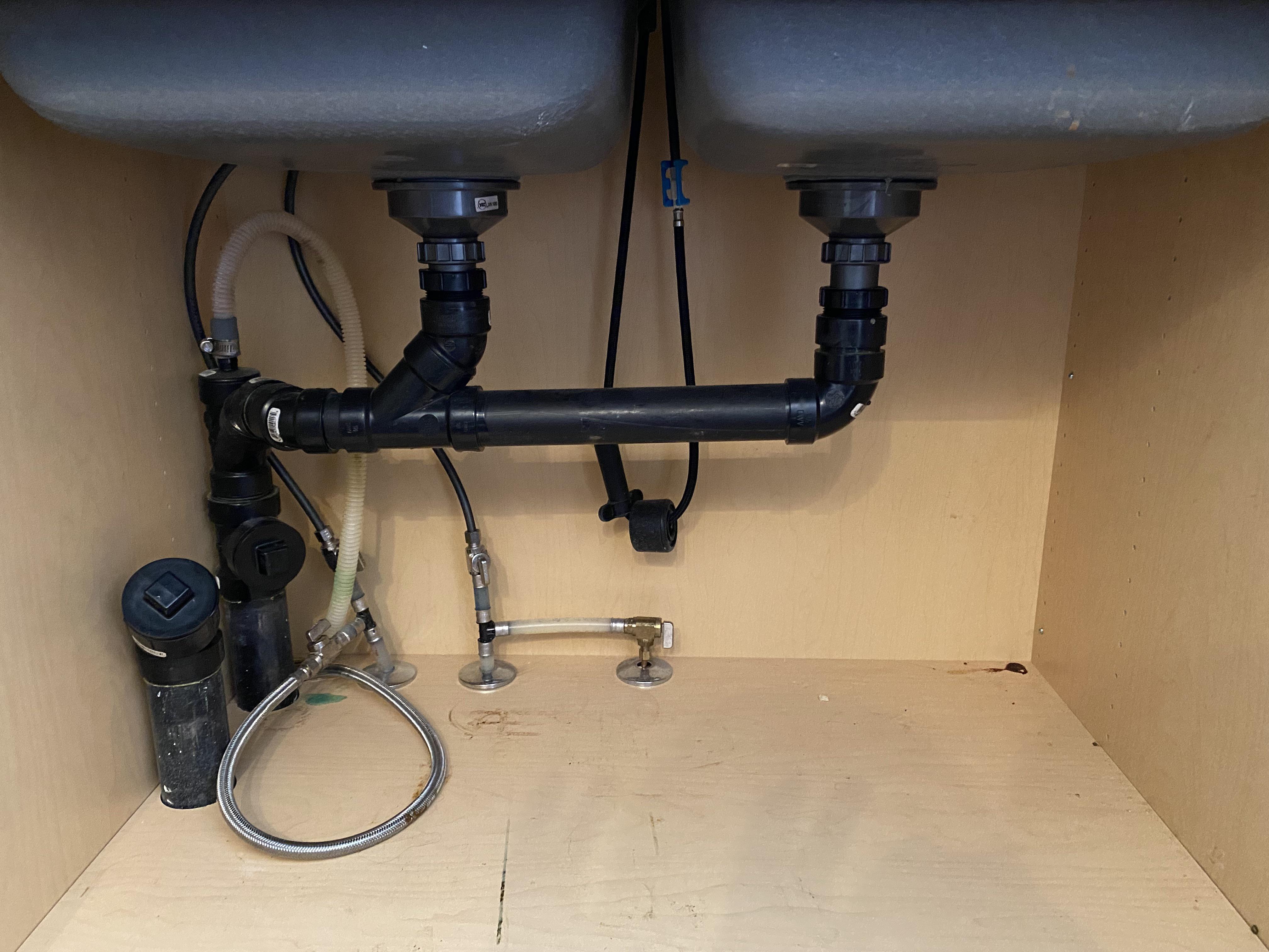 PVC P-trap under a kitchen sink showing the U-shaped bend where the water seal sits