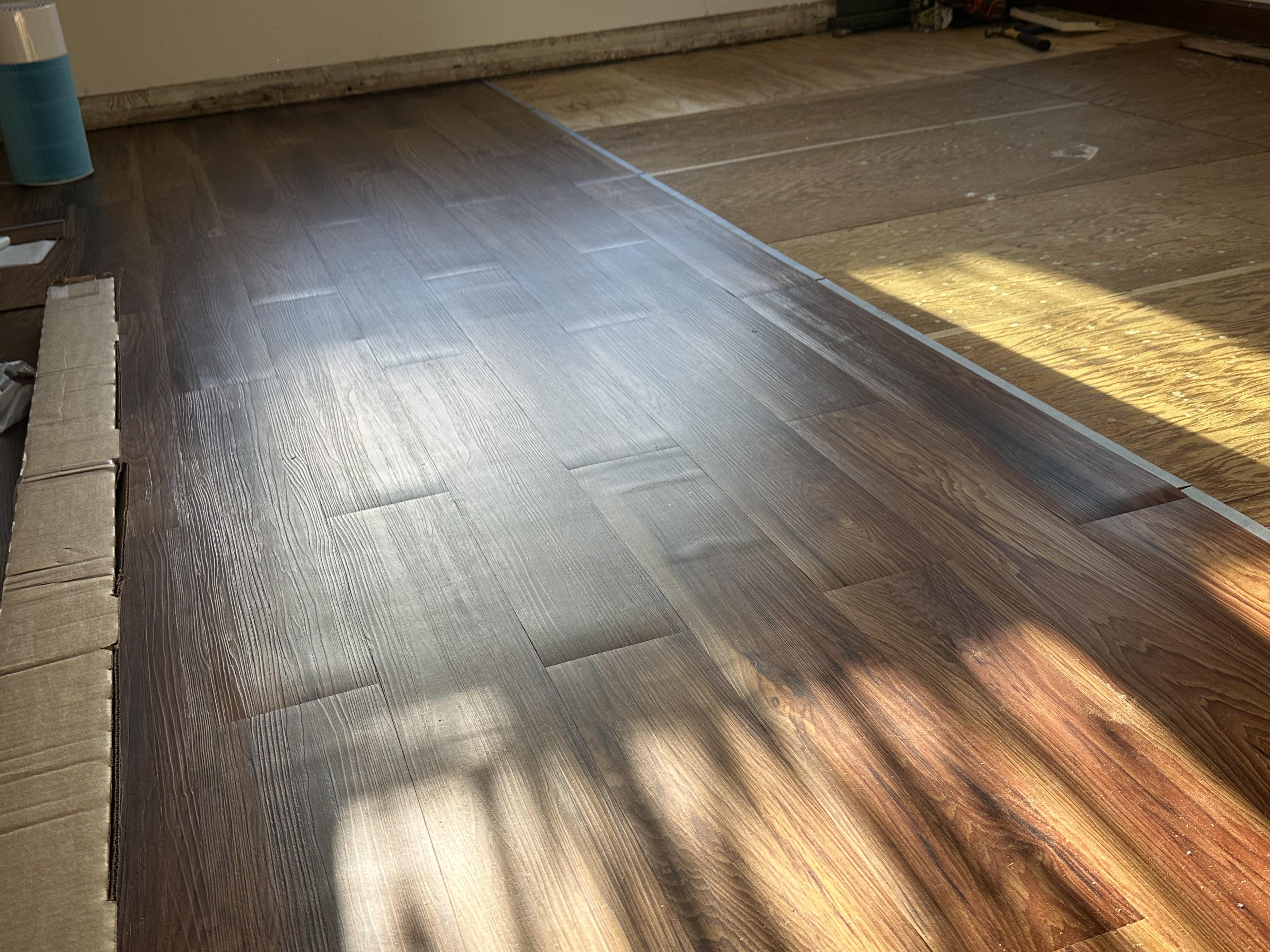 Photo of a vinyl plank floor with a raised ridge running across the room, showing planks tenting upward near the center