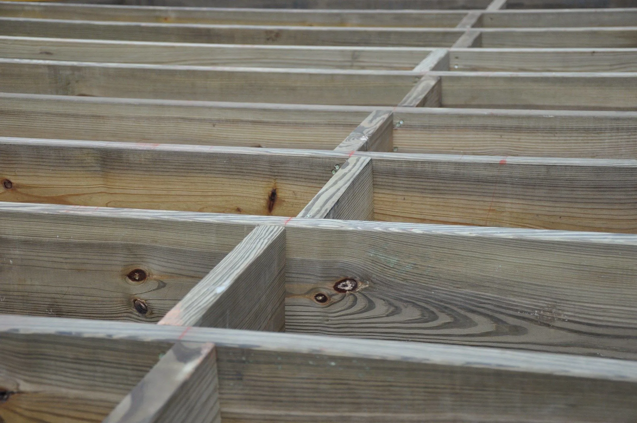 Under a deck showing solid blocking installed between joists with exterior-rated structural screws